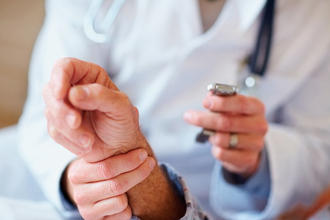 Closeup of a doctor checking an old man's pulse , focus on hands
